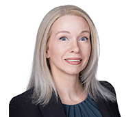 Woman with blonde, shoulder length hair wearing a black blazer and a navy shirt