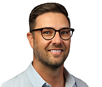 Man with brown hair wearing black glasses and a light blue shirt