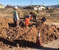 Group of men in hard hats, digging a large dirt hole