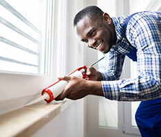 Man sealing air leaks around a window with caulk