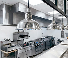 Restaurant kitchen with assorted appliances and overhead lamp lights