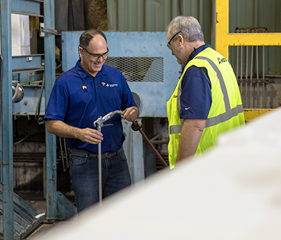 Two men in PPE look at a piece of equipment at Clearwater Paper.