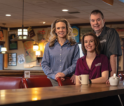 Three employees of Harvester sit at the counter in their business